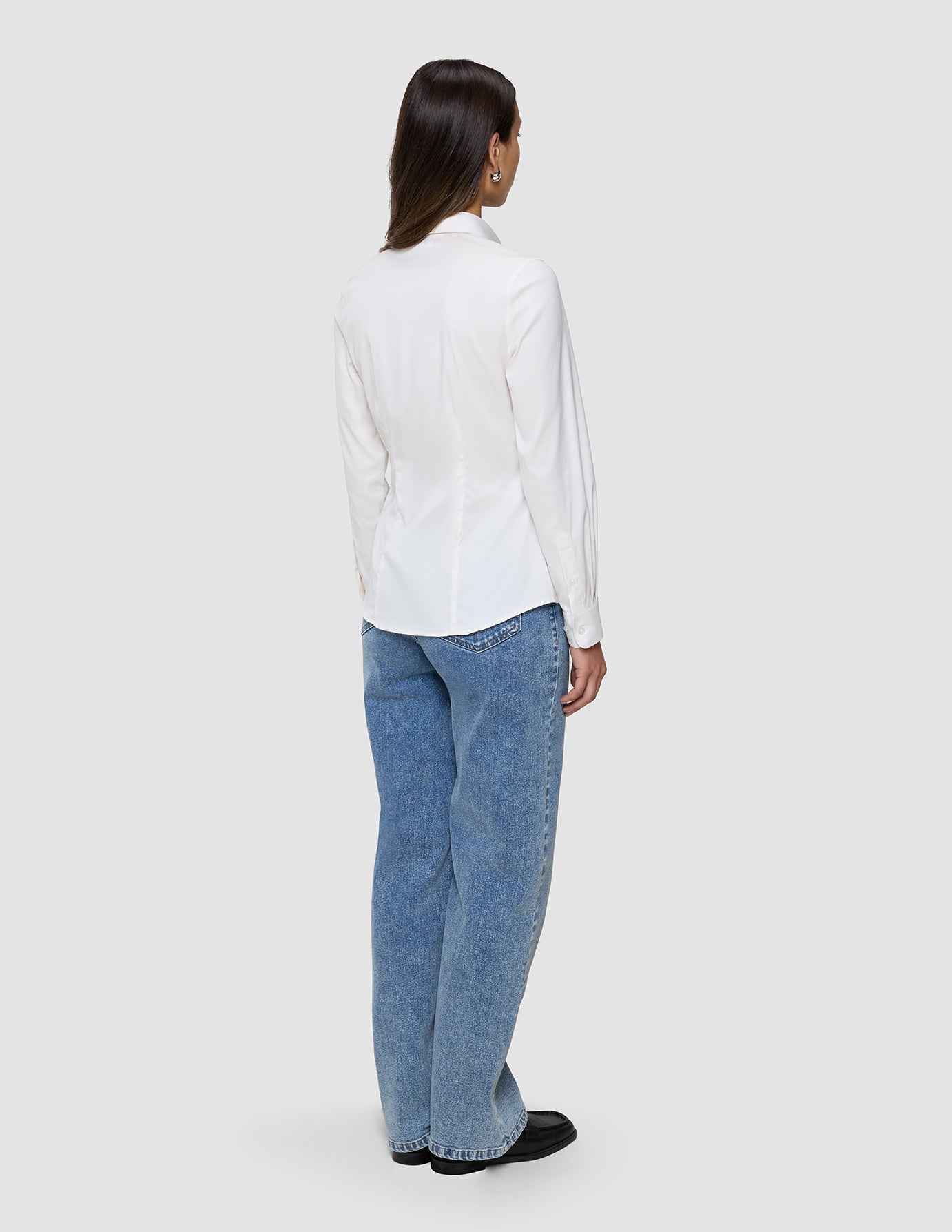 En kvinne sett bakfra, kledd i en Women’s Oxford Shirt White Orchid Slim og blå jeans.